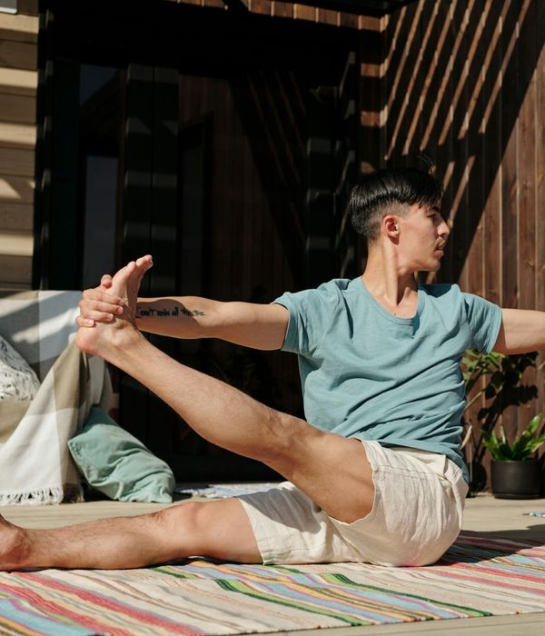 Person holding a difficult balance yoga pose against a bright background.